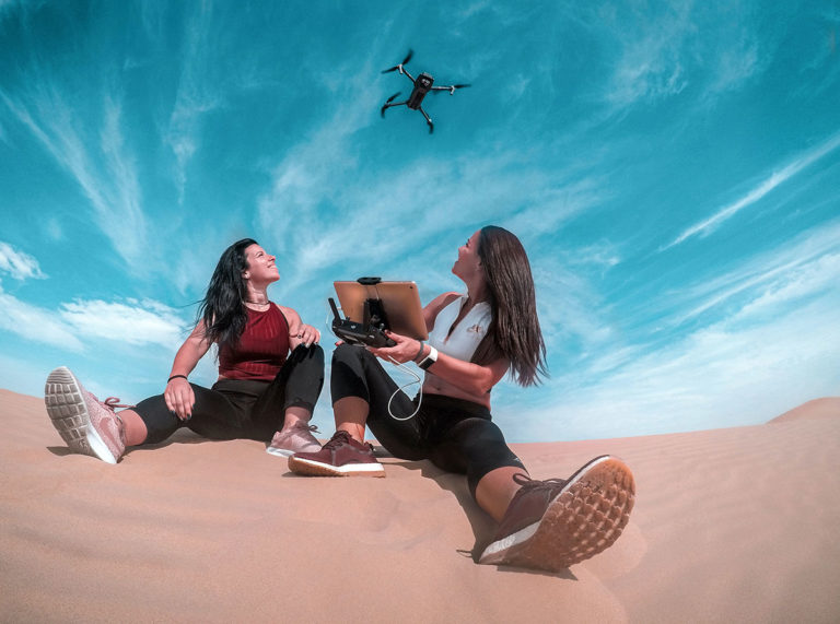 Drones and education - girls using drone in sand.