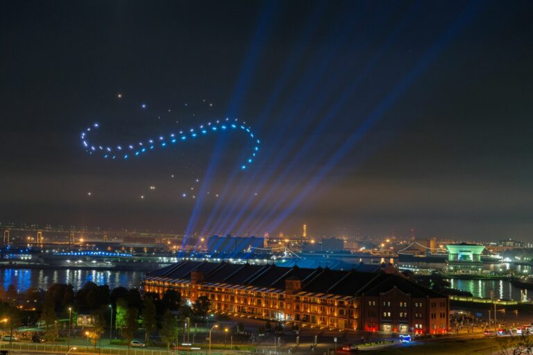 City at night with a drone light show above a large building