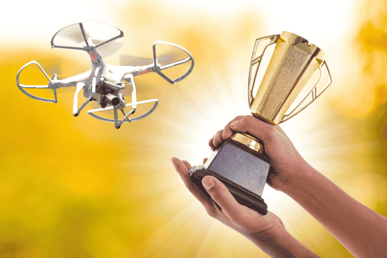 Hand holding a trophy in the direction of a drone winner