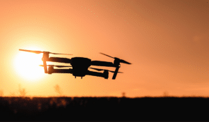 A silhouette of a drone outlined by a beautiful golden orange sunset